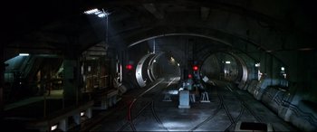 Movie still from “The Italian Job” (2003), directed by F. Gary Gray – A train station with a train on the tracks and lights on; Extreme Wide shot, High angle