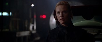 Movie still from “The Italian Job” (2003), directed by F. Gary Gray – A woman in a black jacket is standing in a dark room; Close Up shot, Over the shoulder angle