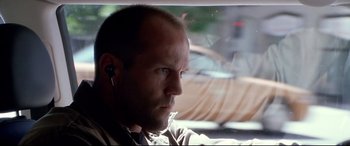 Movie still from “The Italian Job” (2003), directed by F. Gary Gray – A person wearing headphones in a car; Close Up shot, Low angle