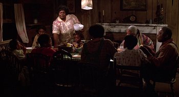 Movie still from “The Jerk” (1979), directed by Carl Reiner – A woman standing at a dinner table with a bunch of children; Wide shot, High angle