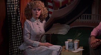 Movie still from “The Jerk” (1979), directed by Carl Reiner – A woman sitting on the ground holding a book; Medium shot, Over the shoulder angle