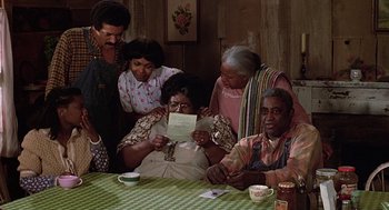 Movie still from “The Jerk” (1979), directed by Carl Reiner – A group of people sitting around a table looking at a piece of paper; Medium shot, High angle