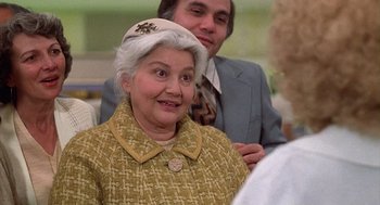 Movie still from “The Jerk” (1979), directed by Carl Reiner – An older woman wearing a hat and a yellow jacket; Close Up shot, Over the shoulder angle