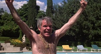 Movie still from “The Jerk” (1979), directed by Carl Reiner – A shirtless man with his hands raised in the air; Medium shot, Low angle