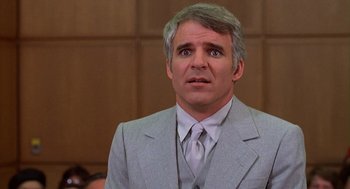 Movie still from “The Jerk” (1979), directed by Carl Reiner – A man wearing a suit and tie in front of a crowd; Close Up shot, Over the shoulder angle