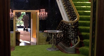 Movie still from “The Jerk” (1979), directed by Carl Reiner – A room filled with stairs and chandeliers next to a table; Extreme Wide shot, High angle