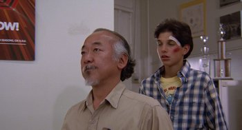 Movie still from “The Karate Kid” (1984), directed by John G. Avildsen – A man and a boy with bandages on their heads; Medium shot, Low angle