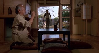 Movie still from “The Karate Kid” (1984), directed by John G. Avildsen – Two people standing in front of an open door; Wide shot, Low angle
