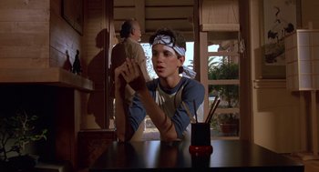 Movie still from “The Karate Kid” (1984), directed by John G. Avildsen – A young boy sitting at a table with a stuffed animal; Medium shot, Over the shoulder angle