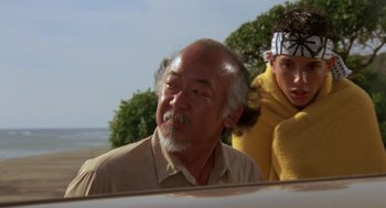 Movie still from “The Karate Kid” (1984), directed by John G. Avildsen – An older man and a young man in a car; Medium shot, Low angle