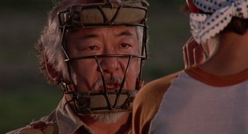 Movie still from “The Karate Kid” (1984), directed by John G. Avildsen – An older man wearing a catchers mask; Close Up shot, Over the shoulder angle