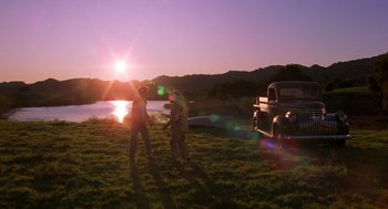 Movie still from “The Karate Kid” (1984), directed by John G. Avildsen – Two people standing in the grass near a truck; Extreme Wide shot, Over the shoulder angle