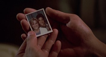 Movie still from “The Karate Kid” (1984), directed by John G. Avildsen – A person holding a picture of a man and a woman; Extreme Close Up shot, High angle