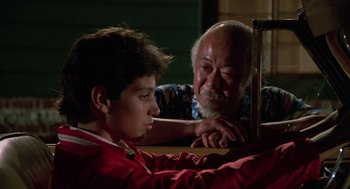 Movie still from “The Karate Kid” (1984), directed by John G. Avildsen – An older man and a young boy looking at each other; Medium shot, Over the shoulder angle