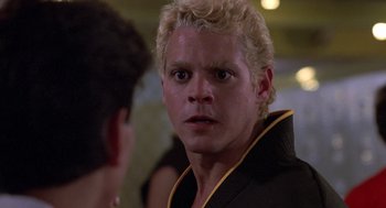 Movie still from “The Karate Kid” (1984), directed by John G. Avildsen – A person wearing a black and yellow jacket; Close Up shot, Over the shoulder angle