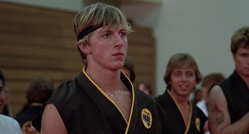 Movie still from “The Karate Kid” (1984), directed by John G. Avildsen – Two young men are practicing martial arts in a gym; Close Up shot, Low angle