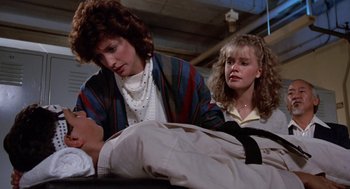 Movie still from “The Karate Kid” (1984), directed by John G. Avildsen – A woman and a girl looking at a man's chest; Medium shot, Low angle