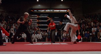 Movie still from “The Karate Kid” (1984), directed by John G. Avildsen – A group of people that are standing up in the air; Wide shot, Low angle