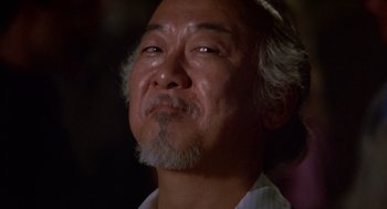 Movie still from “The Karate Kid” (1984), directed by John G. Avildsen – An older man with grey hair looking up; Close Up shot, Low angle