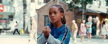 Movie still from “The Karate Kid” (2010), directed by Harald Zwart – A young girl is standing in front of a brick building; Close Up shot, Low angle