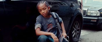 Movie still from “The Karate Kid” (2010), directed by Harald Zwart – A young boy sitting on the side of the road with a bag; Close Up shot, High angle