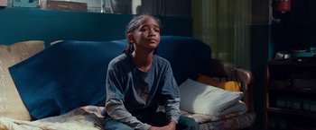 Movie still from “The Karate Kid” (2010), directed by Harald Zwart – A young girl sitting on a couch with her eyes closed; Medium shot, High angle