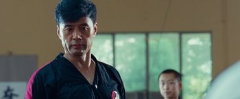 Movie still from “The Karate Kid” (2010), directed by Harald Zwart – A man standing next to another man in a room; Close Up shot, Low angle