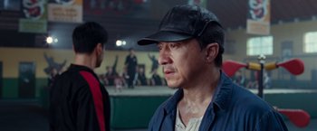 Movie still from “The Karate Kid” (2010), directed by Harald Zwart – A man wearing a black hat and a blue jacket; Close Up shot, Over the shoulder angle