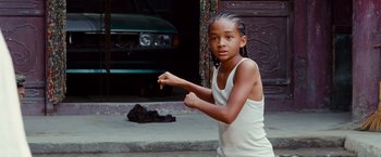 Movie still from “The Karate Kid” (2010), directed by Harald Zwart – A young boy standing on the sidewalk in front of a car; Medium shot, Low angle