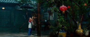 Movie still from “The Karate Kid” (2010), directed by Harald Zwart – A young boy holding a stick while standing next to a tree; Wide shot, Low angle