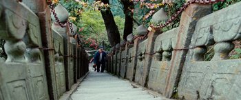 Movie still from “The Karate Kid” (2010), directed by Harald Zwart – A man walking down a stone path next to a tree; Wide shot, High angle