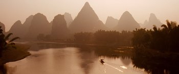 Movie still from “The Karate Kid” (2010), directed by Harald Zwart – A boat is traveling down a river near mountains; Extreme Wide shot, High angle