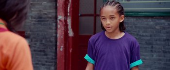 Movie still from “The Karate Kid” (2010), directed by Harald Zwart – A young girl in a purple t - shirt stands in front of a red door; Close Up shot, High angle