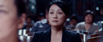Movie still from “The Karate Kid” (2010), directed by Harald Zwart – A woman in a black jacket is looking at the camera; Close Up shot, Over the shoulder angle