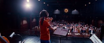 Movie still from “The Karate Kid” (2010), directed by Harald Zwart – A boy playing a violin in front of an audience; Wide shot, Low angle