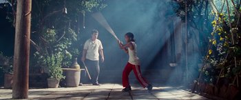 Movie still from “The Karate Kid” (2010), directed by Harald Zwart – A young girl swinging a baseball bat while a man watches; Wide shot, Over the shoulder angle