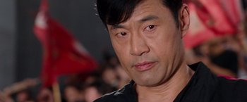 Movie still from “The Karate Kid” (2010), directed by Harald Zwart – A man's face in front of an audience; Close Up shot, Over the shoulder angle