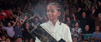Movie still from “The Karate Kid” (2010), directed by Harald Zwart – A young girl holding a telescope in front of an audience; Medium shot, Low angle