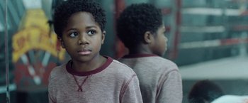 A young boy is looking at his reflection in a mirror