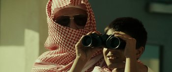 Movie still from “The Kingdom” (2007), directed by Peter Berg – A man and a boy looking through binoculars; Close Up shot, Over the shoulder angle
