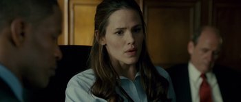 Movie still from “The Kingdom” (2007), directed by Peter Berg – A person sitting in a chair wearing a dress shirt; Close Up shot, Over the shoulder angle