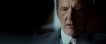 Movie still from “The Kingdom” (2007), directed by Peter Berg – An older man wearing a suit and tie; Close Up shot, Low angle