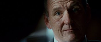 Movie still from “The Kingdom” (2007), directed by Peter Berg – A man's face in a suit and tie; Close Up shot, Low angle