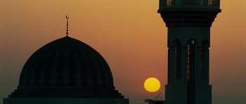 Movie still from “The Kingdom” (2007), directed by Peter Berg – The sun is setting behind a building in the distance; Extreme Wide shot, Low angle