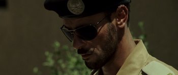 Movie still from “The Kingdom” (2007), directed by Peter Berg – A person wearing sunglasses and a hat; Close Up shot, Low angle