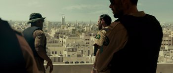 Movie still from “The Kingdom” (2007), directed by Peter Berg – Two men looking out over a city from a building; Medium shot, Over the shoulder angle