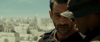 Movie still from “The Kingdom” (2007), directed by Peter Berg – A person wearing a hat; Close Up shot, Over the shoulder angle