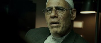 Movie still from “The Kingdom” (2007), directed by Peter Berg – An older man wearing glasses and a white hat; Close Up shot, Over the shoulder angle