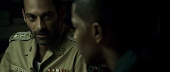 Movie still from “The Kingdom” (2007), directed by Peter Berg – Two men in military uniforms sitting next to each other; Close Up shot, Over the shoulder angle