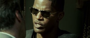 Movie still from “The Kingdom” (2007), directed by Peter Berg – A person wearing sunglasses; Close Up shot, Over the shoulder angle
